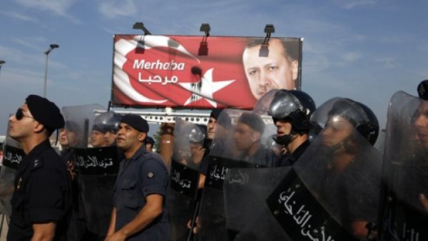 رجال امن لبنانيون يحرسون لافتة لاردوغان خلال تظاهرة مناهضة لزيارته في بيروت