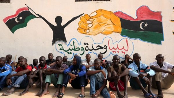 Illegal migrants sit in front of a painted wall on May 19, 2016 at the Abu Salim detention center in Tripoli, Libya. (AFP/Mahmud Turkia)