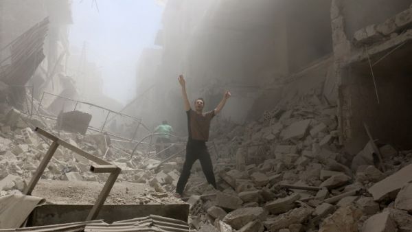A man gestures while walking through rubble after multiple airstrikes in Aleppo today. (AFP/Amee Alhalbi)
