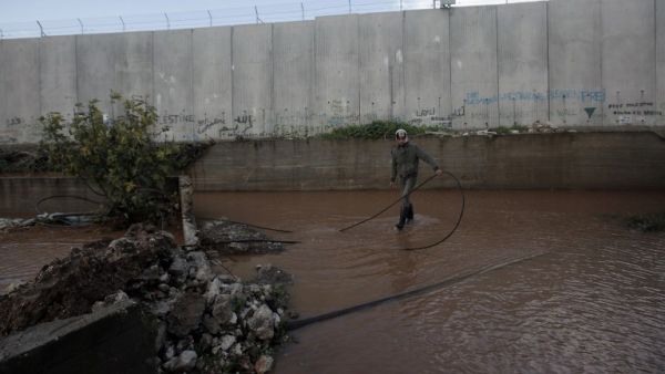 A Palestinian boy stands in a flooded area adjacent to Israel's controversial separation barrier near the West Bank city of Qalqilya (AFP PHOTO/JAAFAR ASHTIYEH)