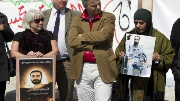 Layla Issawi (R) holds a picture of her son Samer Issawi, a Palestinian held in Israeli jail and on hunger strike for more than 200 days. (AFP PHOTO/AHMAD GHARABLI)