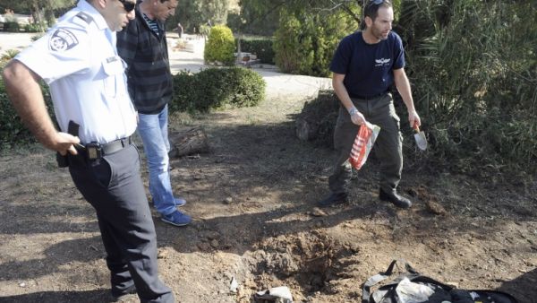 A bomb technician collects the remains of a rocket launched from Gaza Strip falling close to Sderot on April 3, 2013. Israeli aircraft carried out apparent warning strikes in the Gaza Strip, hitting empty fields after a militant rocket earlier struck waste ground in southern Israel. (AFP PHOTO/DAVID BUIMOVITCH)