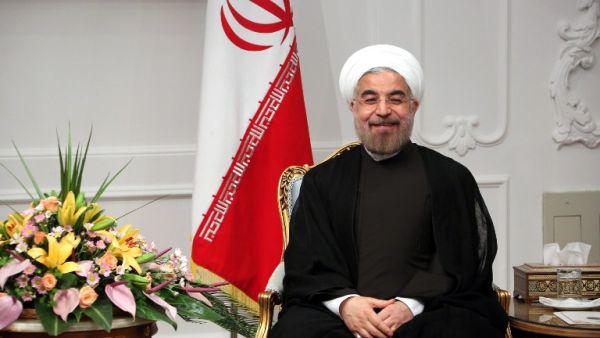  Iran's new President Hassan Rouhani sits next to the national flag on his first official day in office in Tehran on August 3, 2013. (AFP)