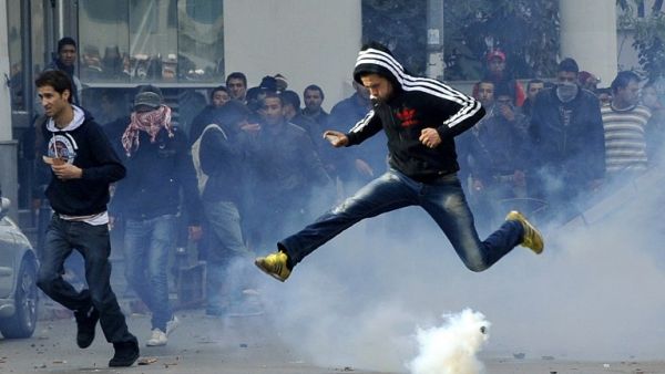 A Tunisian protester jumps amid smoke after police fired tear gas during a rally outside the Interior ministry to protest after Tunisian opposition leader and outspoken government critic Chokri Belaid was shot dead. AFP PHOTO / FETHI BELAID A Tunisian protester jumps amid smoke after police fired tear gas during a rally outside the Interior ministry to protest after Tunisian opposition leader and outspoken government critic Chokri Belaid was shot dead. AFP PHOTO / FETHI BELAID
