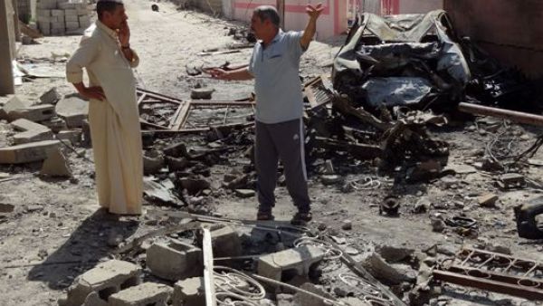 Iraqis talk on the site where a suicide bomber detonated an explosives-rigged vehicle on August 11, 2013 in the northern city of Tuz Khurmatu. Car bombs ripped through Baghdad cafes and markets while blasts and shootings struck elsewhere on August 10, killing 61 people as Iraq marked the end of its deadliest Ramadan holy month in years. (AFP)