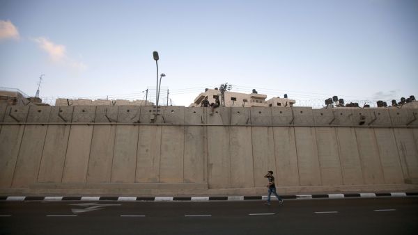Palestinian men prepare to jump using a rope over a section of Israel's controversial concrete barrier that separates the West Bank from Jerusalem on August 12, 2013, in Beit Hanina, in Israeli annexed east Jerusalem. (AFP)
