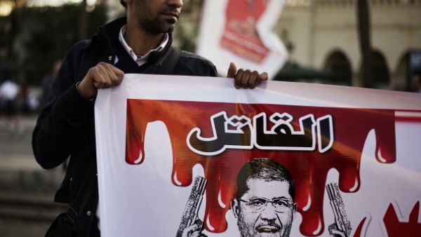 An Egyptian anti-government protester holds a poster mocking Egypt's President Mohamed Morsi during a demonstration outside the presidential palace in Cairo on February 8, 2013. [Getty Images]