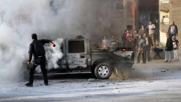 An Egyptian policeman tries to extinguish a police vehicle set on fire by Muslim Brotherhood supporters on a ring road in the capital, Cairo, on January 3, 2014. [Getty Images]