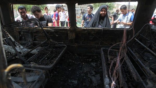 By-standers look at the wreck of a bomb used in a sectarian suicide attack in Baghdad. AFP Photo