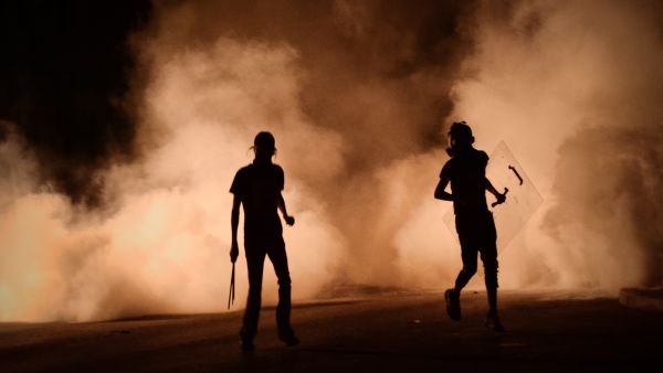Bahraini protestors run for cover during clashes with riot police following a protest against the ruling regime (AFP/MOHAMMED AL-SHAIKH)