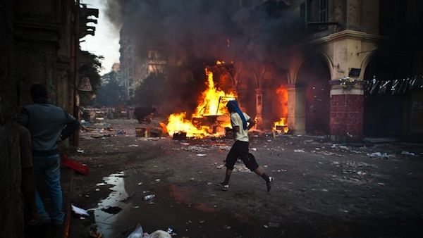 A supporter of the Muslim Brotherhood and of ousted president Mohamed Morsi runs past a burning vehicle during clashes with security officers close to Cairo's Ramses Square, on August 16, 2013. (AFP)