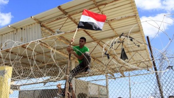 A Palestinian protestor puts up an Egyptian flag on barbed wire during a rally in front of the Rafah border crossing in the southern Gaza Strip on September 16, 2013. (AFP)