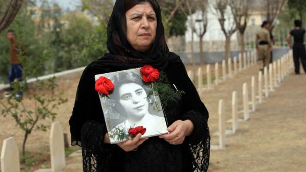 An Iraqi Kurdish woman visits the grave of her sister, who was killed in a gas attack by former Iraqi president Saddam Hussein in 1988 (AFP Photo)