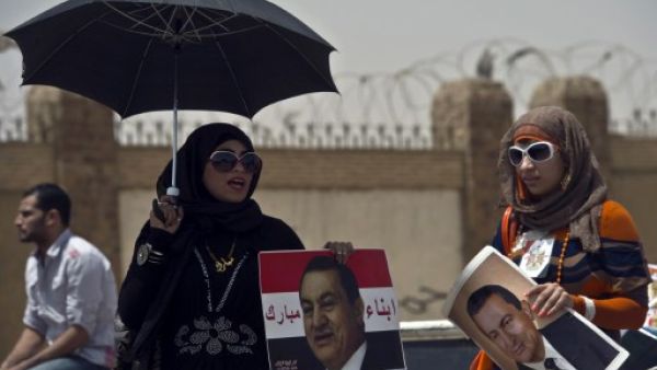 Egyptian female supporters of Egypt's former president Hosni Mubarak, hold portraits of him outside the Egyptian police academy in Cairo. AFP
