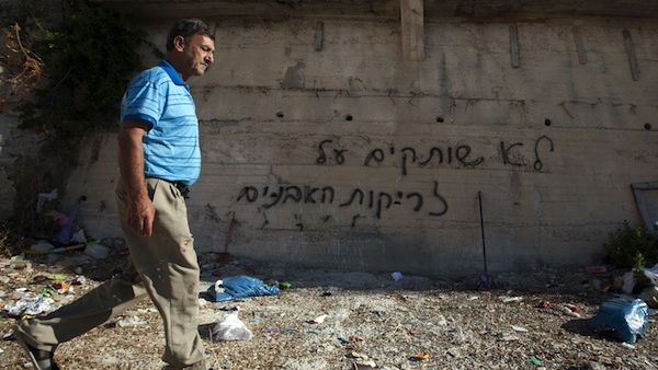 A Palestinian man was past graffiti that reads in Hebrew, "'We do not remain silent in face of stone throwing" as he walks past a wall in the Arab east Jerusalem neighborhood of Beit Hanina, on Monday. (AFP)