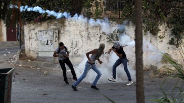 A Palestinian protester hurls a smoke grenade back at Israeli soldiers during clashes in Betunia near the West Bank city of Ramallah on September 20, 2013 (AFP)