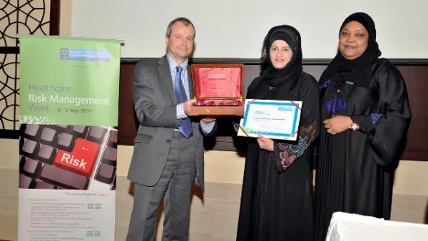 Dr. Moza Alishaq hands over a memento of appreciation to Gary Needle in the presence of Dr. Badriya Al Ali
