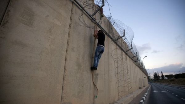  A Palestinian man jumps using a rope over a section of Israel's controversial concrete barrier that separates the West Bank from Jerusalem on August 12, 2013. (AFP)