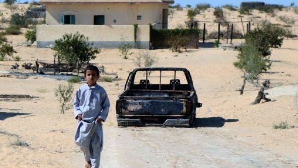 An Egyptian child walks in front of the wreckage of a burnt down car, the day after an attack by Egyptian Army in a village on the outskirt of the Northern Sinai (AFP)
