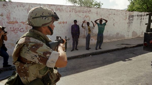 A U.S. Marine points a weapon at gunmen who are surrendering after a Marine patrol confiscated their weapons on December 21, 1992, near the Parliament building along Mogadishu's green line. (AFP)
