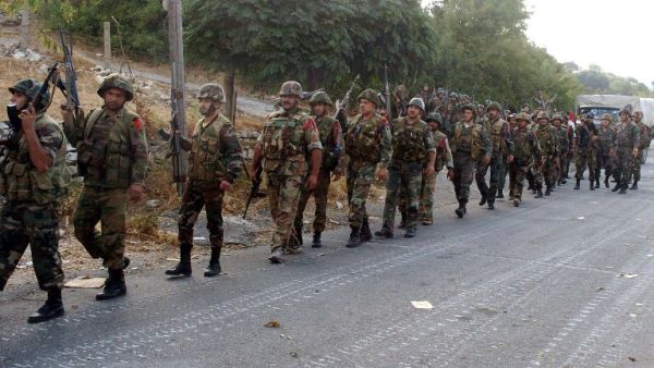 Syrian army soldiers walk on a road during an alleged pursuit of opposition fighters in the Latakia province, western Syria on August 8. (AFP/SANA)