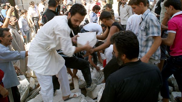 Rescuers and neighboors removes chunks of rubble from a partially collapsed building after a rocketed slammed into the side of a residential block located next to a mosque in the northern city of Aleppo on June 29, 2013. (Source: AFP/JALAL-ALHALABI)