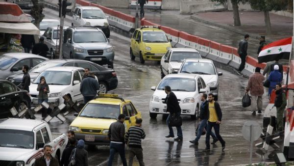 Syrians walk past cars in central Damascus on December 3, 2013 prior to a suicide attack in the Jebbeh district of the capital causing deaths and injuries, Syrian state television reported. (AFP)