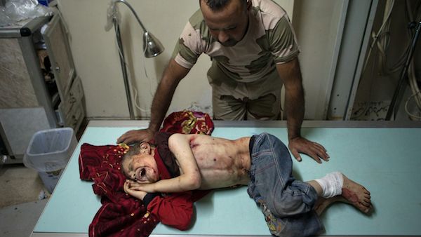 An opposition fighter stands over seven year old Ahmad Jabir, who was injured alongside some of his family members by a shell (Source: AFP/DANIEL LEAL OLIVAS)