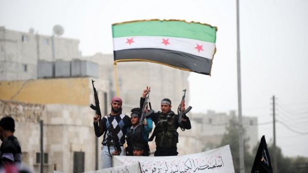 Syrian rebels raise their weapons under a pre-Baath Syrian flag currently used by the opposition during an anti-regime protest in the northern city of Aleppo. (AFP PHOTO/BULENT KILIC)