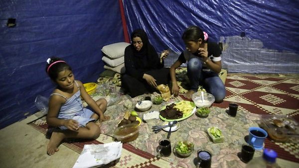 Fatima (C) a Syrian refugee widow, who lost her husband during the fighting in Homs, and her daughters have their Ramadan dinner in their makeshift room in a neighborhood of the Lebanese coastal city of Tripoli (AFP/JOSEPH EID)