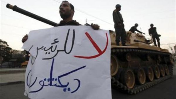 متظاهر مناهض لمرسي يحمل لافتة ويقف امام دبابة امام قصر الرئاسة في القاهرة