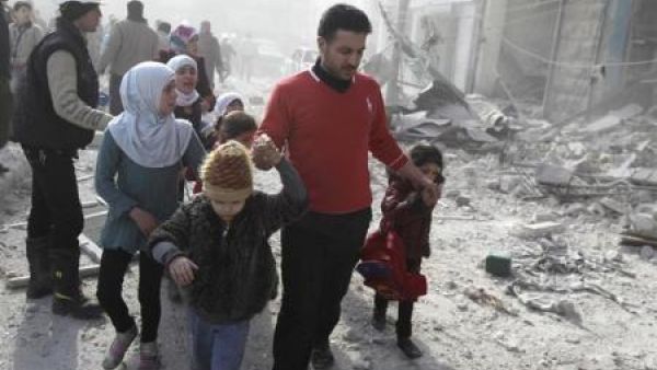 شخص يقود بعض الاطفال من منطقة مدمرة في حلب
