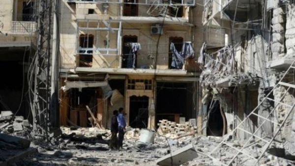 سوريون يتفقدون مبنى تعرض لغارة جوية في حلب
