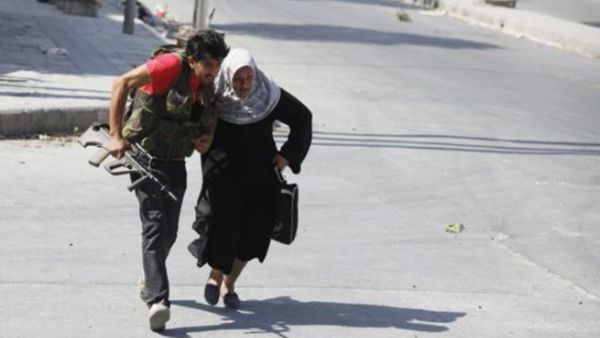مقاتل من الجيش الحر يساعد امراة على عبور الشارع خلال الاشتباكات في حلب
