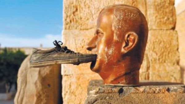 تمثال للرئيس السوري الراحل حافظ الاسد وقد دس احدهم حذاء في فمه