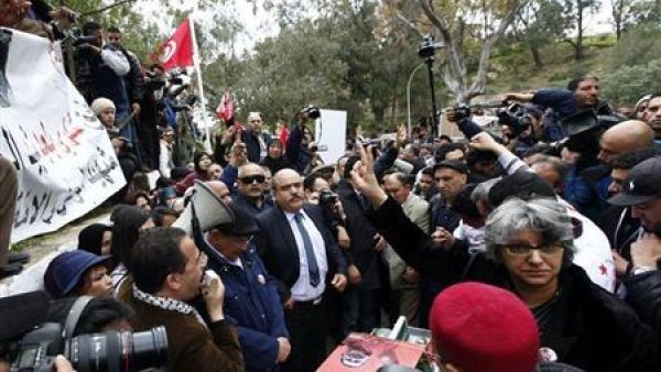 بسمة ارملة بلعيد تلوح بعلامة النصر مع مجموعة من اقارب زوجها الراحل امام قبره 
