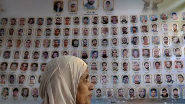 فلسطينية امام لافتة تحمل صور واسماء السجناء الفلسطينيين في السجون الاسرائيلية امام مبنى الصليب الاحمر في القدس الشرقية
