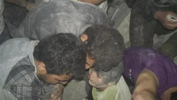 صبي (في الوسط) عقب استخراجه من بين ركام مبنى تهدم في غارة جوية بمنطقة قرب درعا يوم الأحد