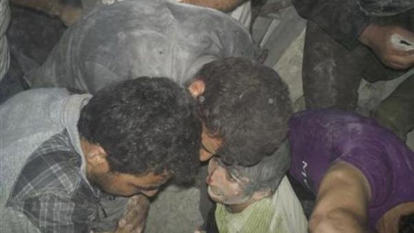 صبي (في الوسط) عقب استخراجه من بين ركام مبنى تهدم في غارة جوية بمنطقة قرب درعا يوم الأحد