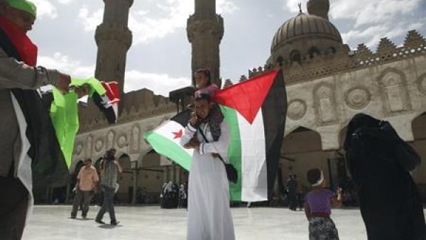 رجل يحمل ابنته وفي يده علمي فلسطين وسوريا داخل الجامع الازهر بالقاهرة
