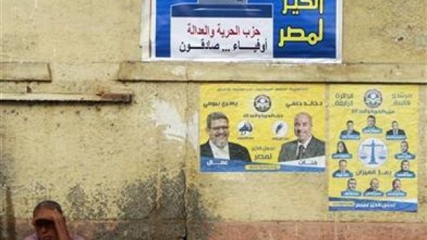 مصري يجلس في شارع أسفل ملصقات انتخابية بالقاهرة