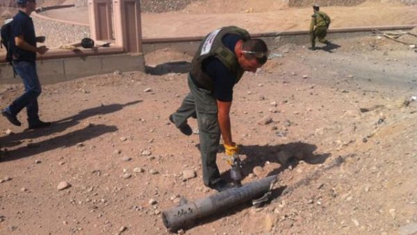 An Eilat policeman picks up a piece of one of the rockets (Courtesy of Haaretz/Eilat Police)