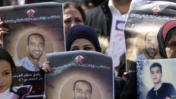 فلسطينيون يرفعون صورا للعيساوي الاسير الفلسطيني المضرب عن الطعام
