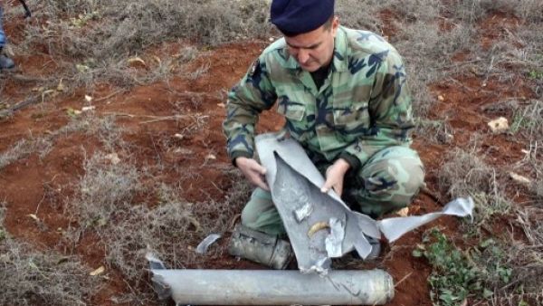 A Lebanese soldier examines one of the shells fired into his country's southern territory from Israel Sunday (Ali Dia/AFP)