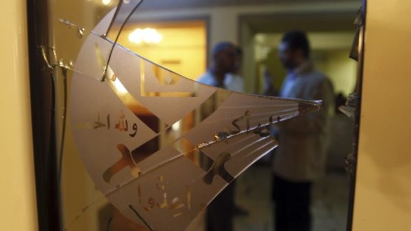 عضوان في الاخوان يبدوان خلف البوابة المحطمة لمقر الجماعة في القاهرة