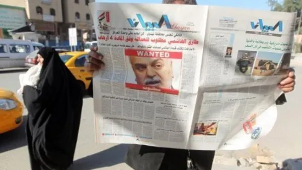 عراقي يقرأ صحيفة تصدرت صفحتها الاولى قصة امر اعتقال الهاشمي