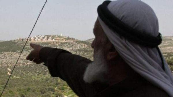 شيخ فلطسيني يشير الى مستوطنة في الضفة الغربية