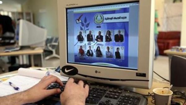 عامل يصمم ملصق حملة انتخابية لمرشحي الجبهة الوطنية ببنغازي في انتخابات المؤتمر الوطني العام في ليبيا يوم الأحد
