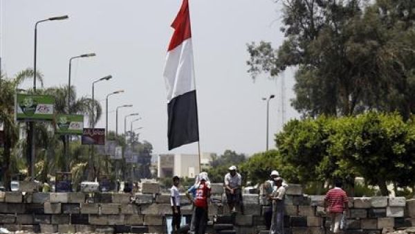 مجموعة من جماعة الاخوان المسلمين ومؤيدو المصري المعزول محمد مرسي يجلسون عند حاجز بميدان رابعة العدوية في القاهرة
