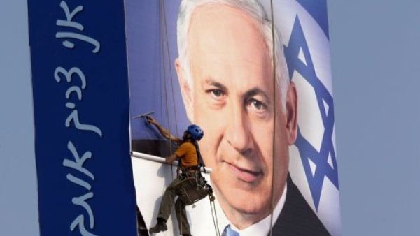 رجل يقوم بتثبيت ملصق انتخابي لرئيس الوزراء الاسرائيلي بنيامين نتانياهو